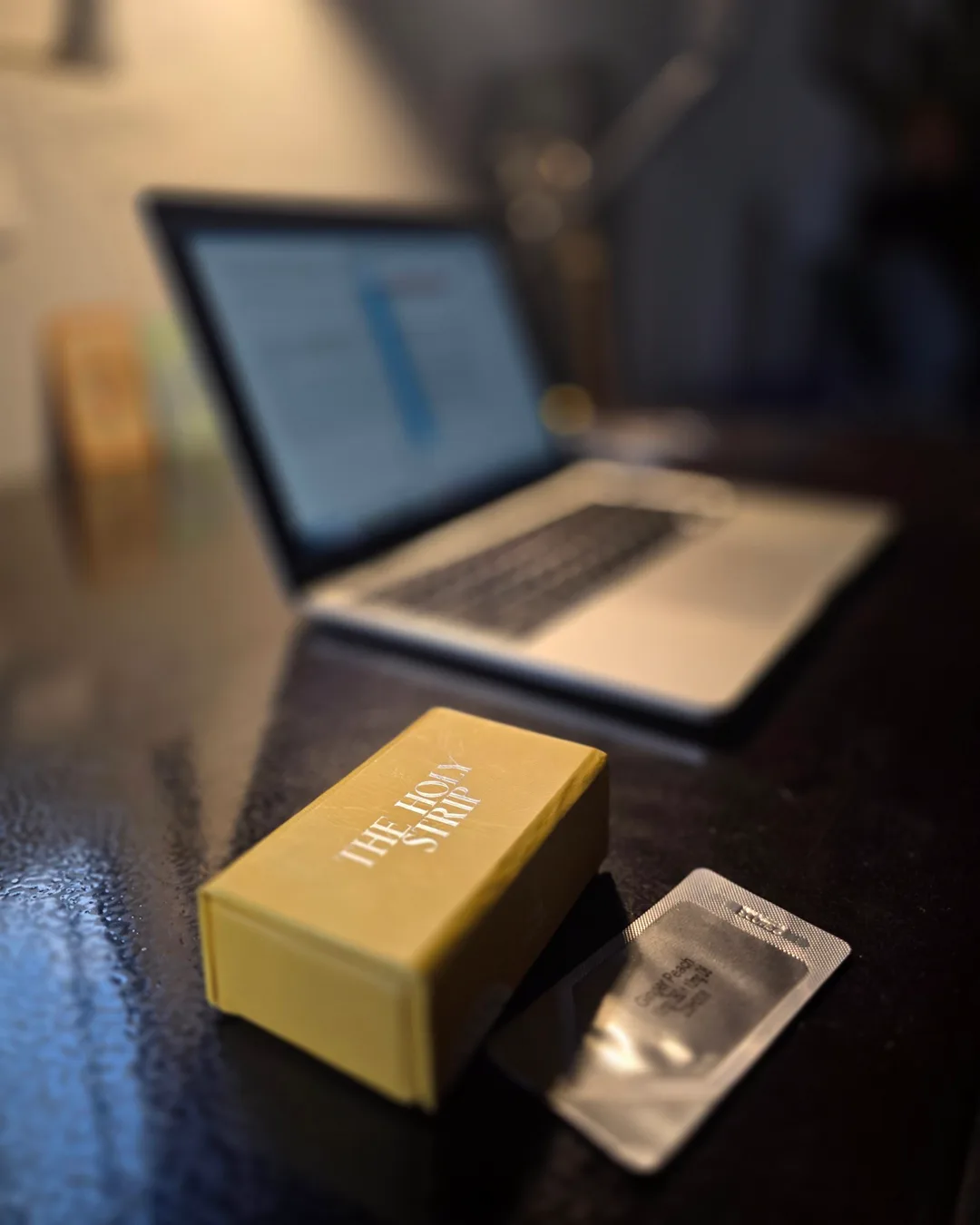 Foto de una caja amarilla de producto sobre un escritorio, tomada con un teléfono.